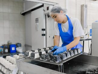 Woman with a Blue Apron and Gloves Producing White Cheese in a Factory