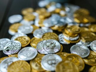 A collection of gold and silver cryptocurrency coins including Bitcoin and Ethereum on a dark surface.