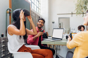 Businesswoman watching VR goggles by colleague at workplace