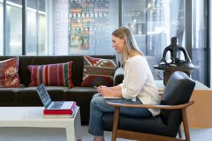 woman in white long sleeve shirt sitting on red and brown couch